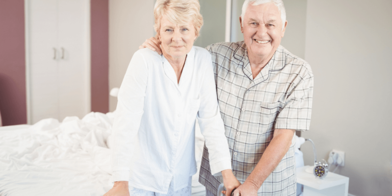 Elder couple and man arm around woman looking at the cost of assisted living